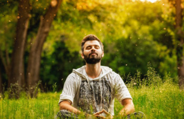 Мужчина сидит на траве и медитирует